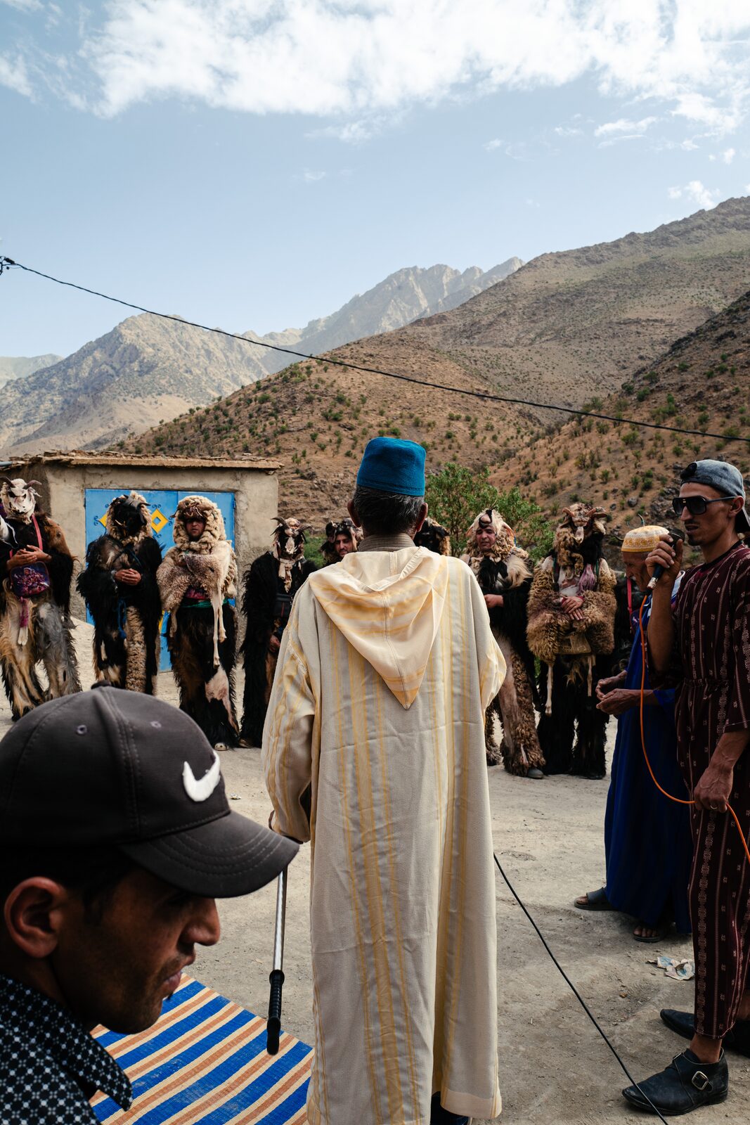 Man in a cream djellaba facing a crowd in a mountain village — Abderrahmane Ajja for ZELZAL