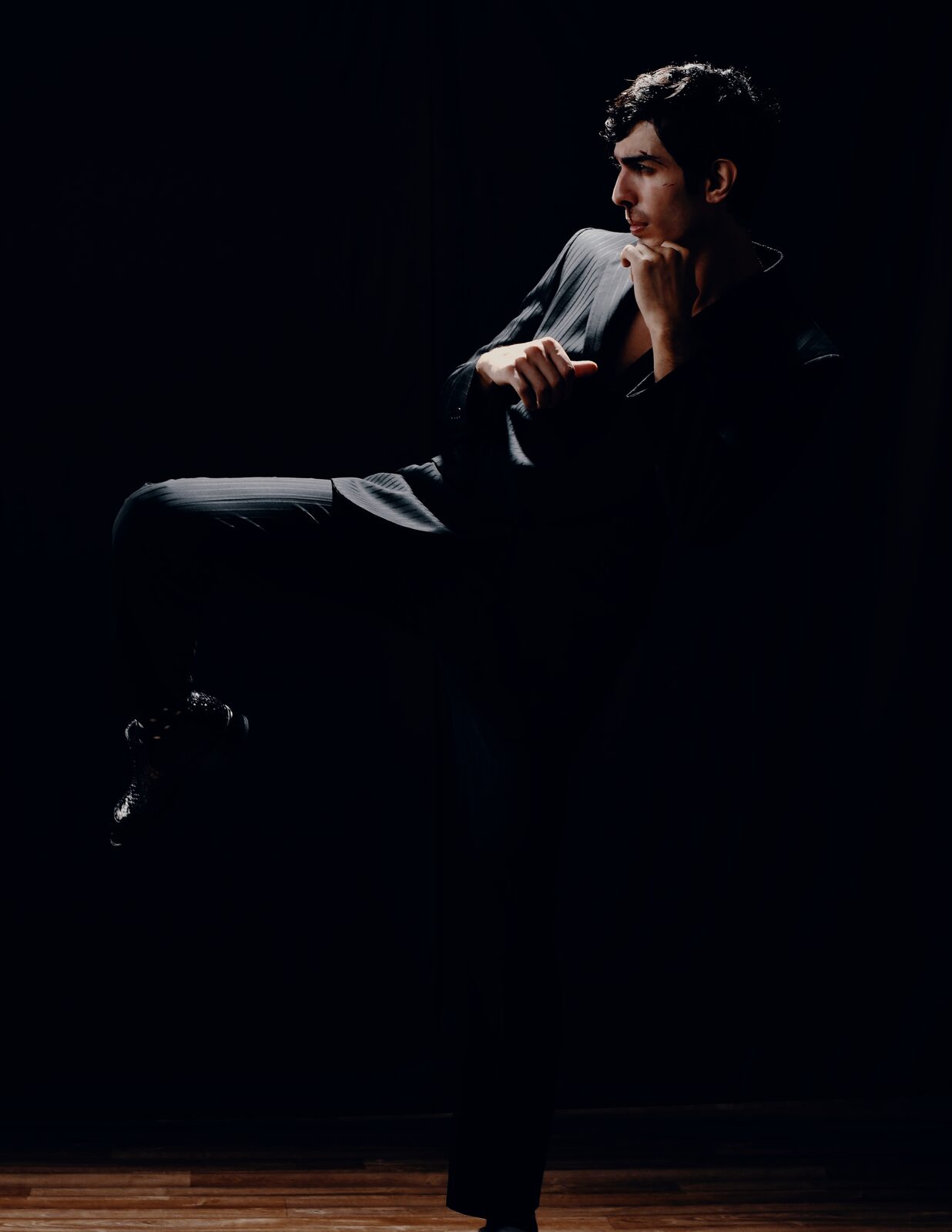 Man in black mid-kick on a dark stage — Abdullah Al Zanki for ZELZAL