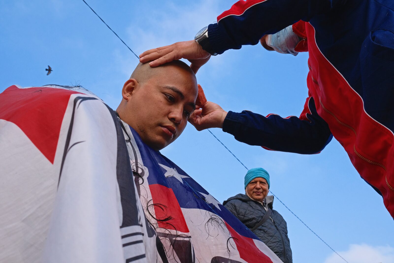 Man raising a red, white and blue flag over a boy's head against blue sky — Angelo for ZELZAL