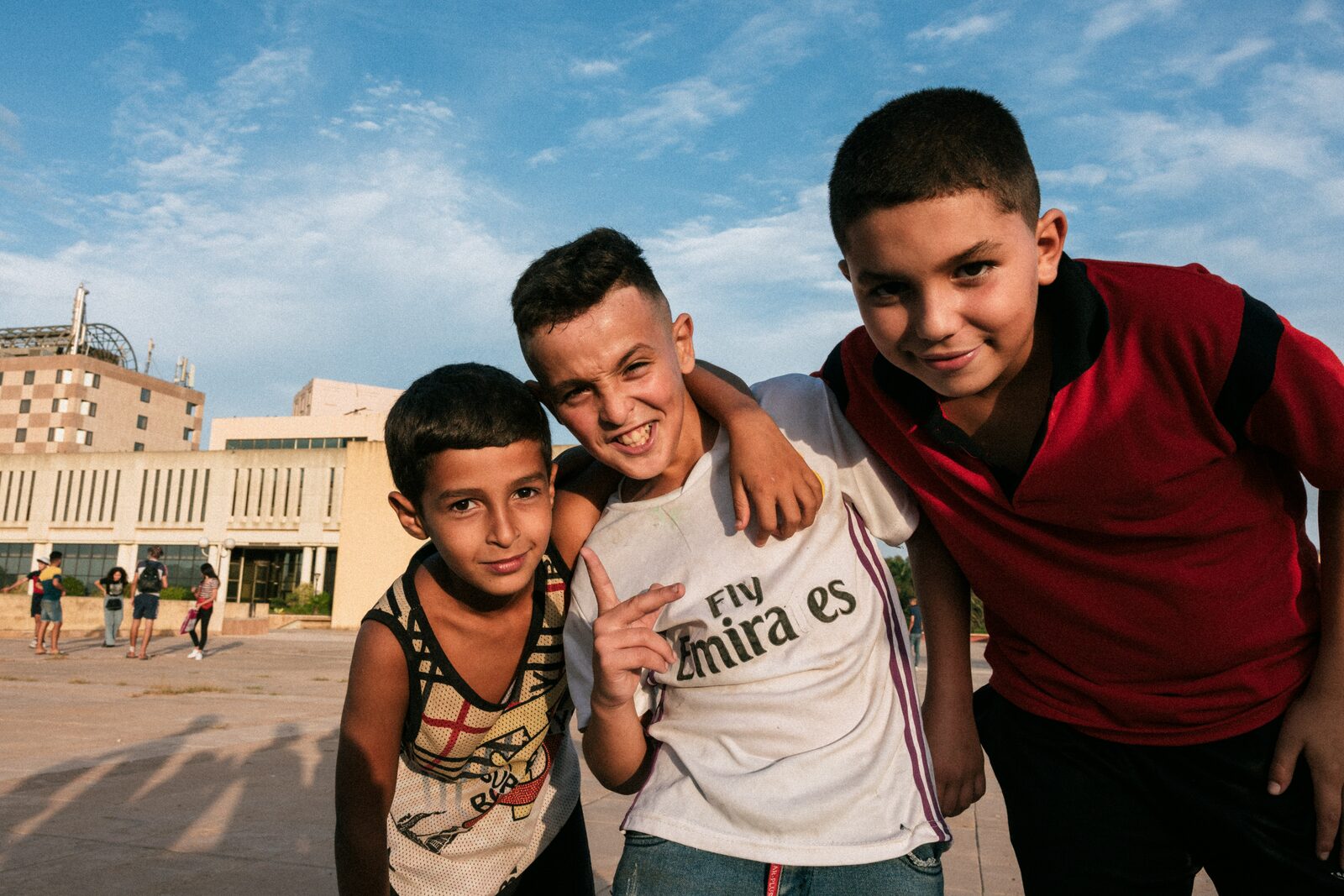 Three boys posing arm in arm on a square — Aqib Anwar for ZELZAL