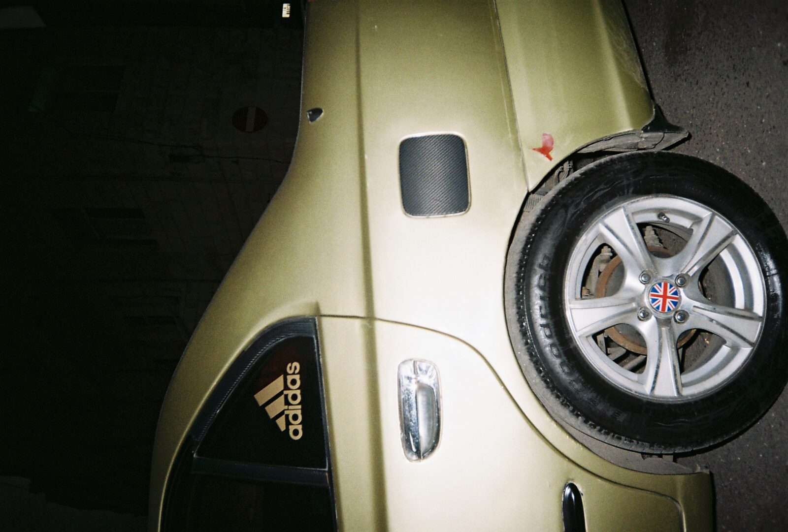 Flash-lit side of a car with an Adidas sticker by the wheel — Basel Hassan for ZELZAL