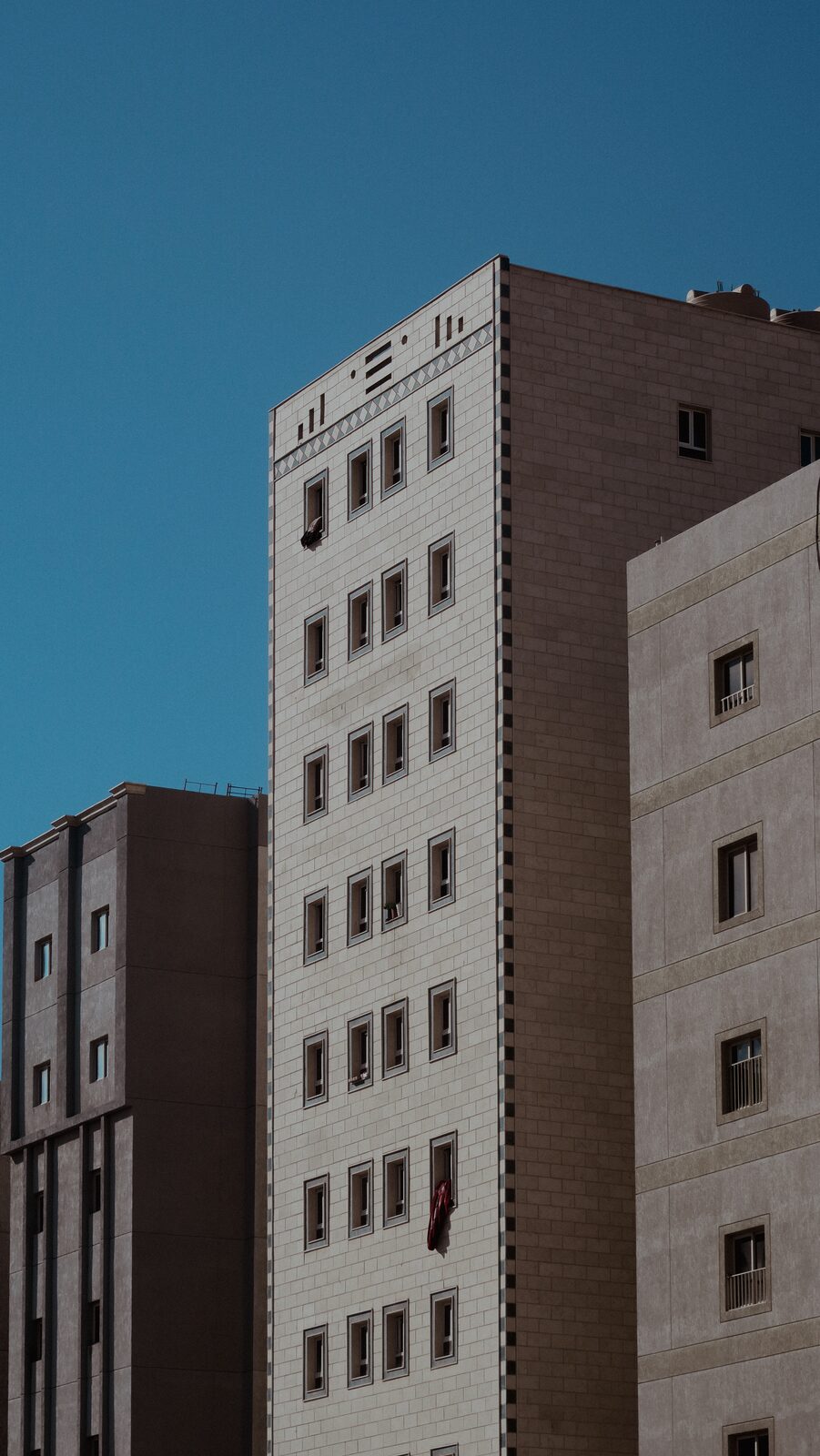 Apartment tower against a deep blue sky — Bashar Belal for ZELZAL