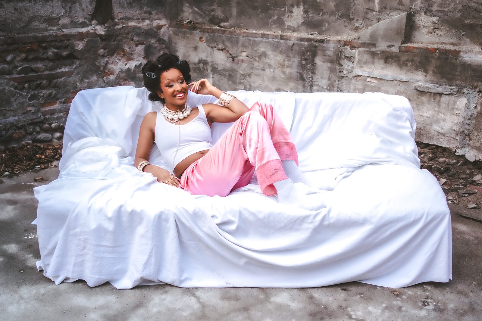 Woman in pink trousers lounging on a white-draped sofa outdoors — HunchoSwf / Sawssen Fajr for ZELZAL