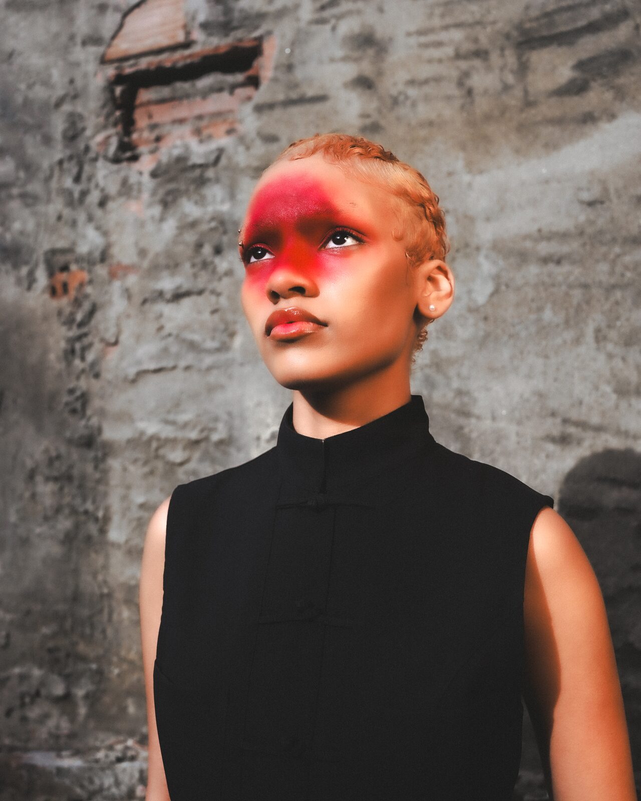 Portrait of a woman with red face paint against a stone wall — HunchoSwf / Sawssen Fajr for ZELZAL