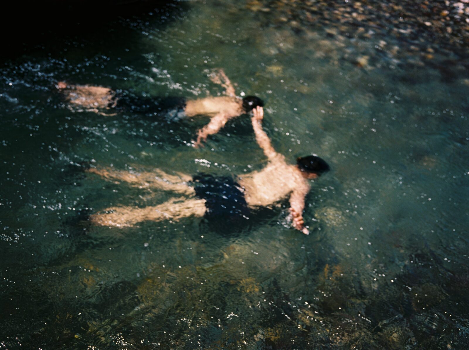 Two swimmers seen from above in dark water — Ilias El Faris for ZELZAL