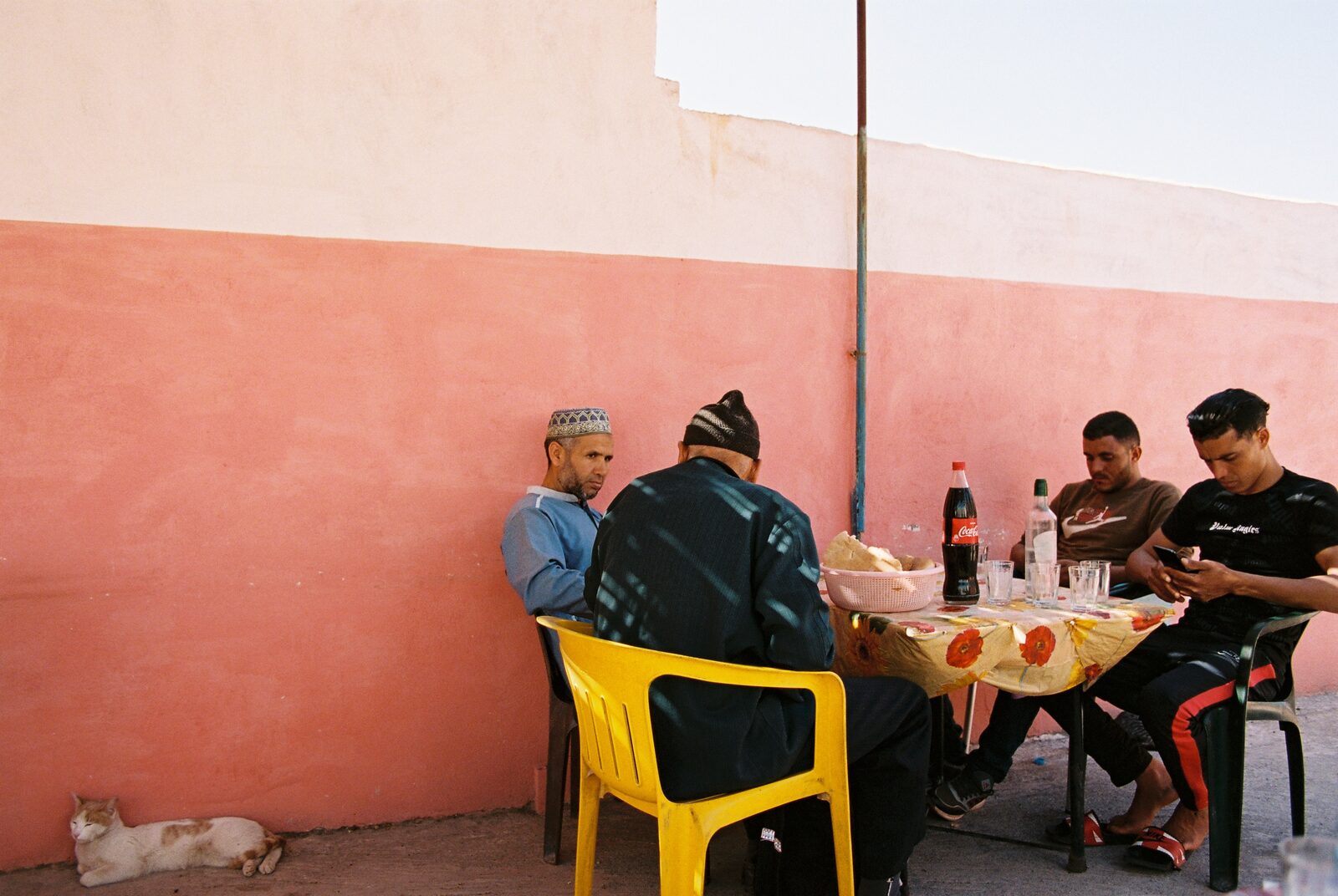 Men eating at a table against a pink wall — Ilias El Faris for ZELZAL
