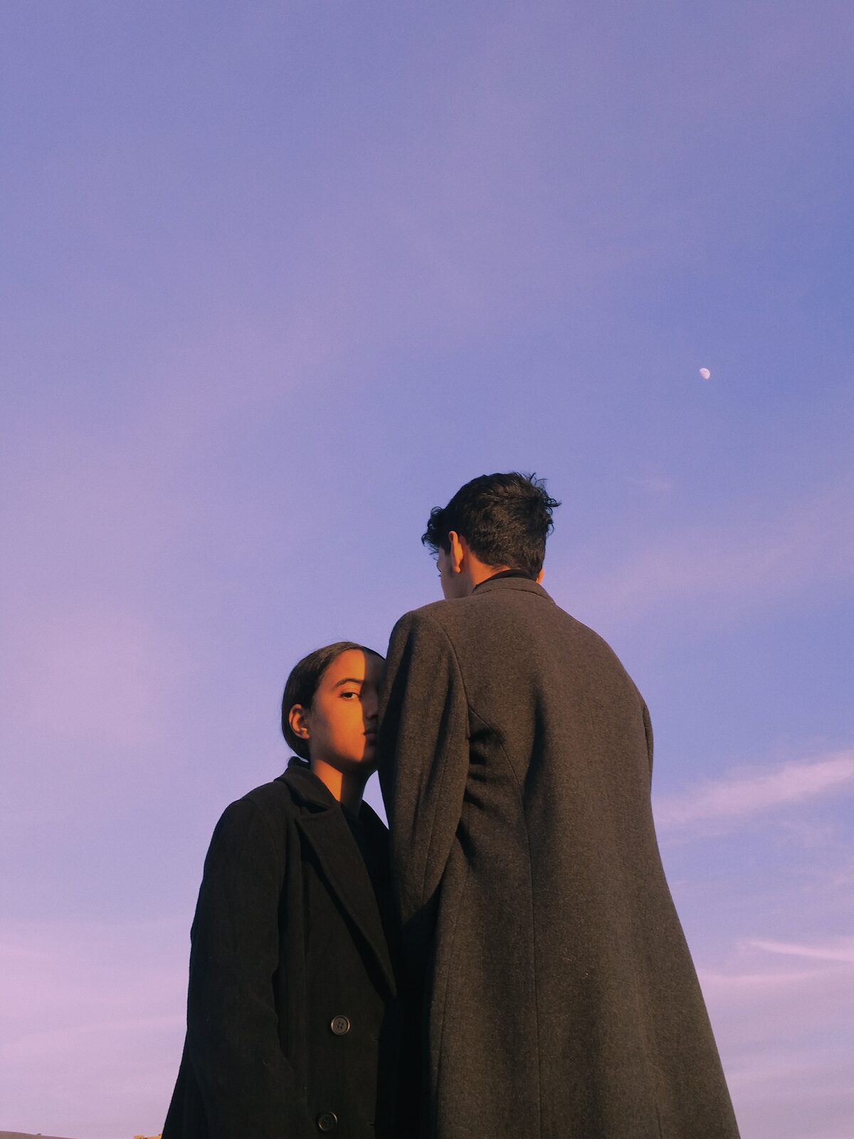 Two figures in long coats against a lilac sky — Ismail Zaidy for ZELZAL