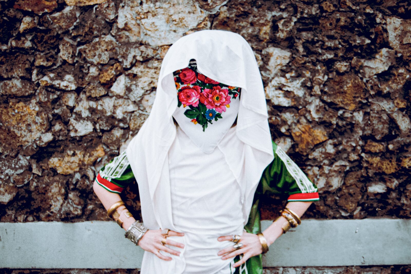 Model in a white veil with a floral face covering against rock — Rahim Rabia for ZELZAL