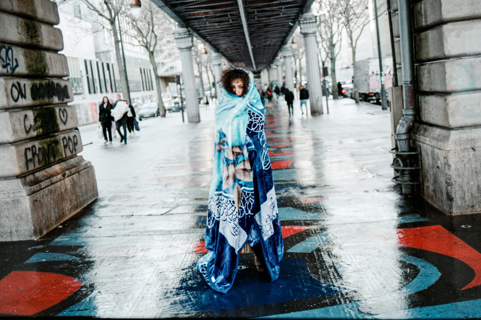 Model in a blue patterned robe on a wet street under a viaduct — Rahim Rabia for ZELZAL