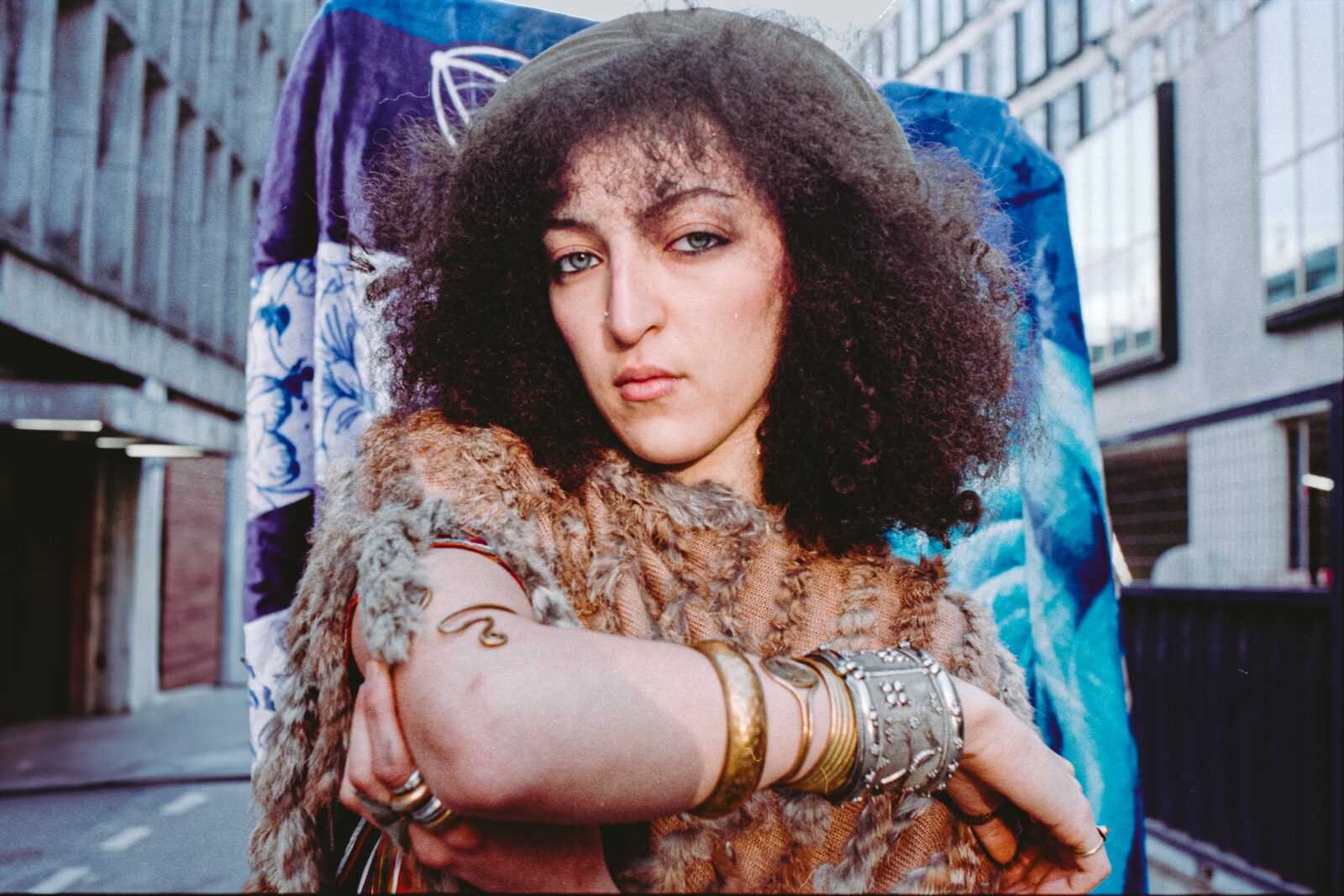 Model with curly hair and silver bracelets, arms crossed — Rahim Rabia for ZELZAL