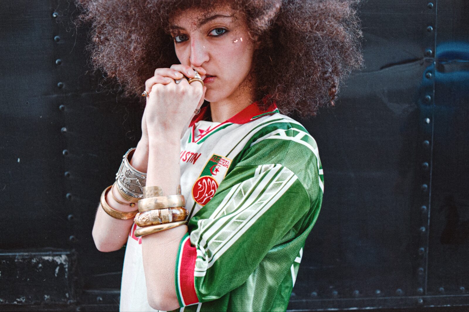 Model in a green football jacket with hands clasped — Rahim Rabia for ZELZAL