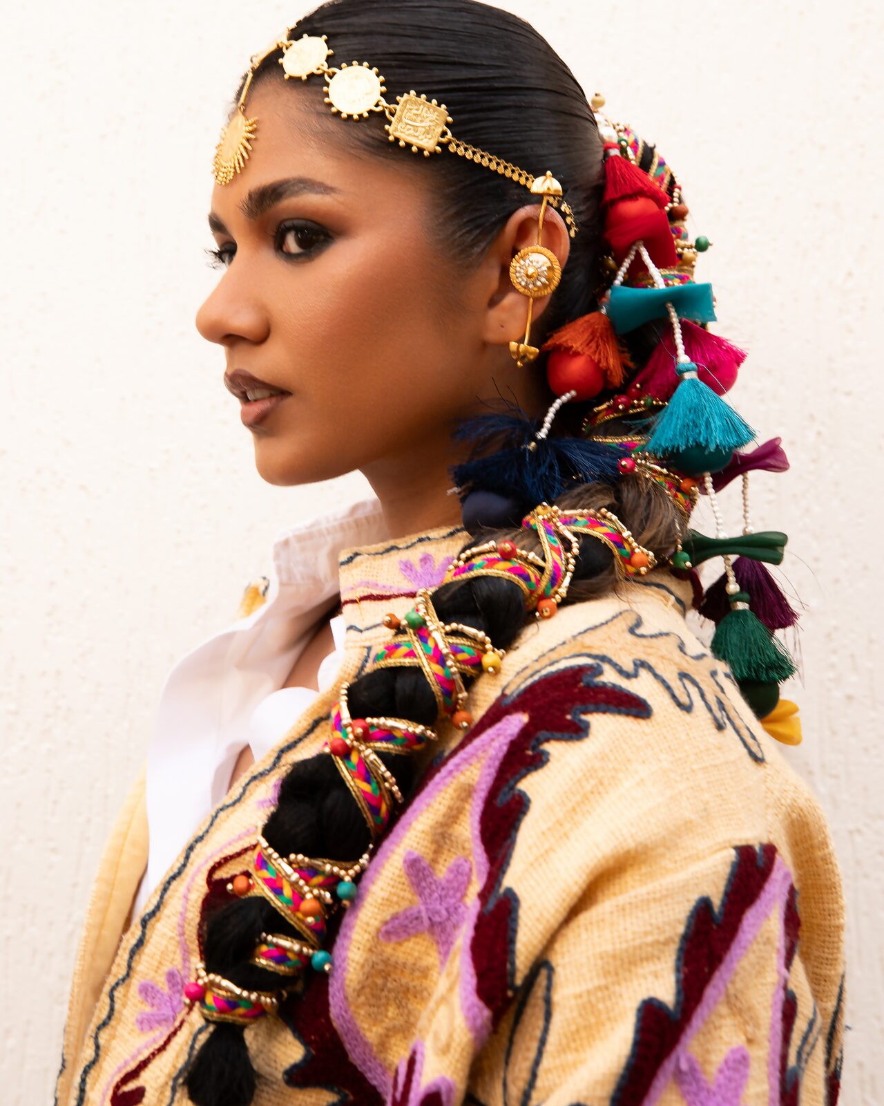 Profile of a model with gold head jewellery and braided tassels — Ron John for ZELZAL