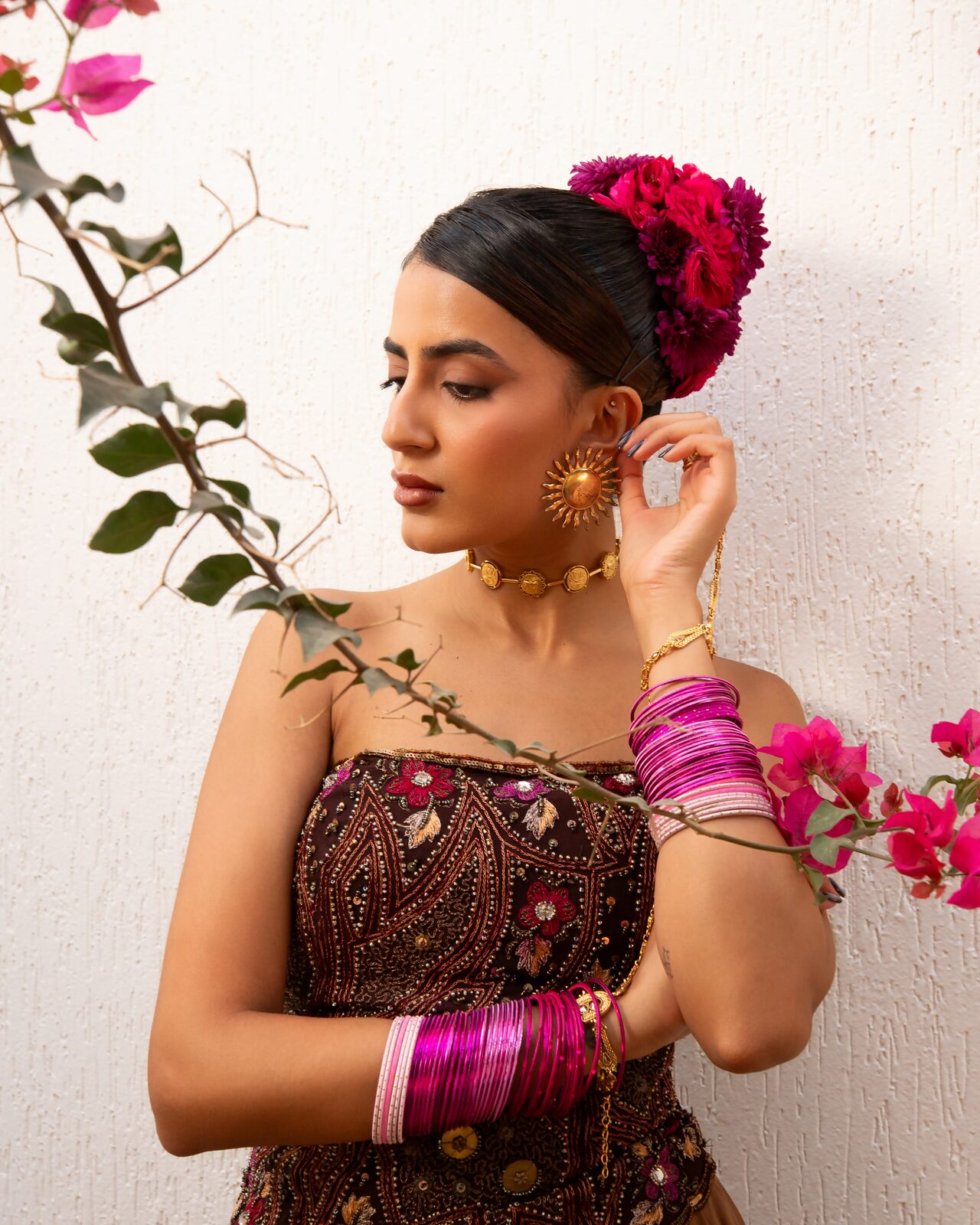Model with flowers in her hair and pink bangles beside bougainvillea — Ron John for ZELZAL
