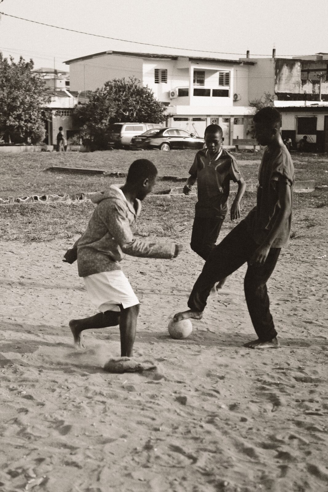 Sepia boys playing football on sand — Rosario Nandjui for ZELZAL
