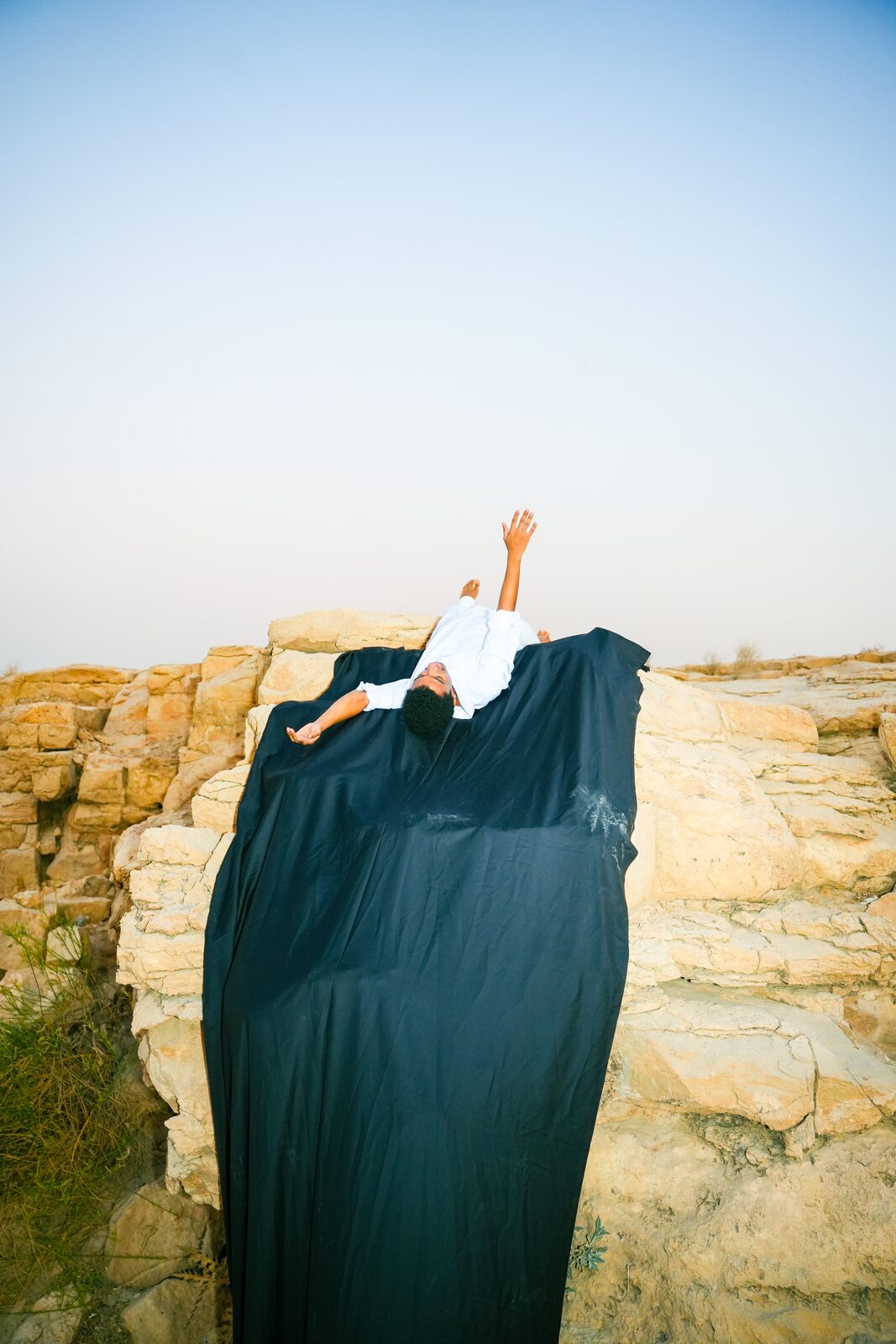 Figure lying on rocks over a long dark fabric — Salem Hamed Al Shammari (Traceofsalem) for ZELZAL