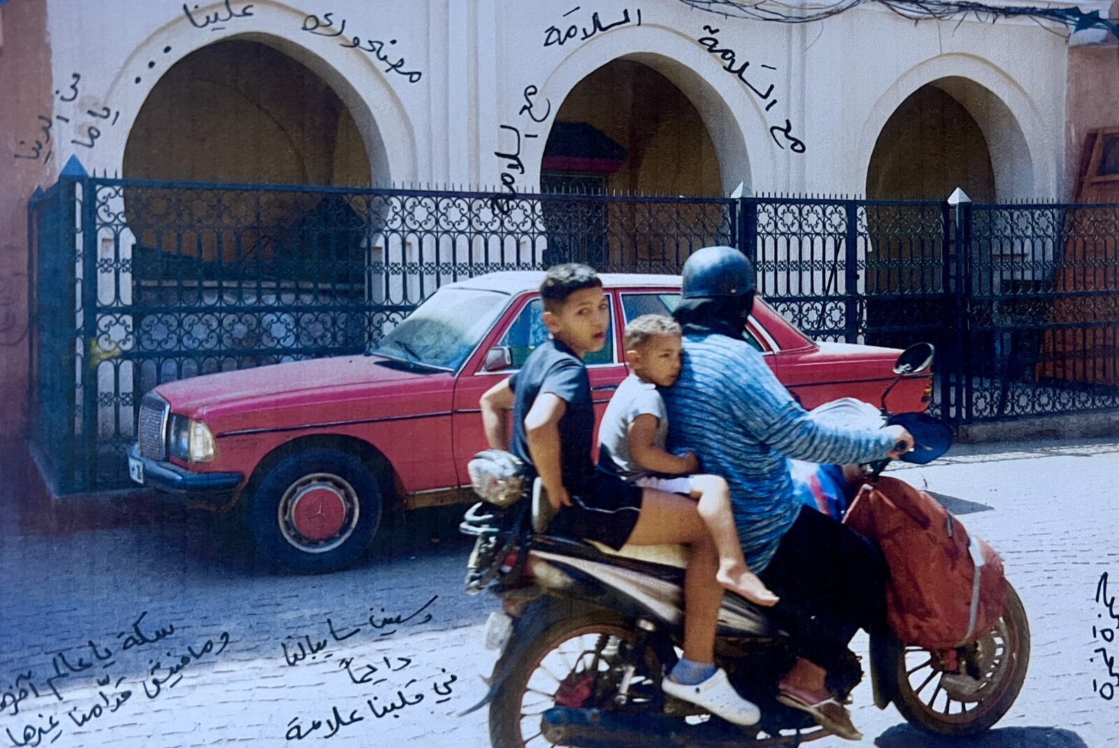 Family on a scooter by a red car, with Arabic handwriting — Shams Al-Fekaiki for ZELZAL