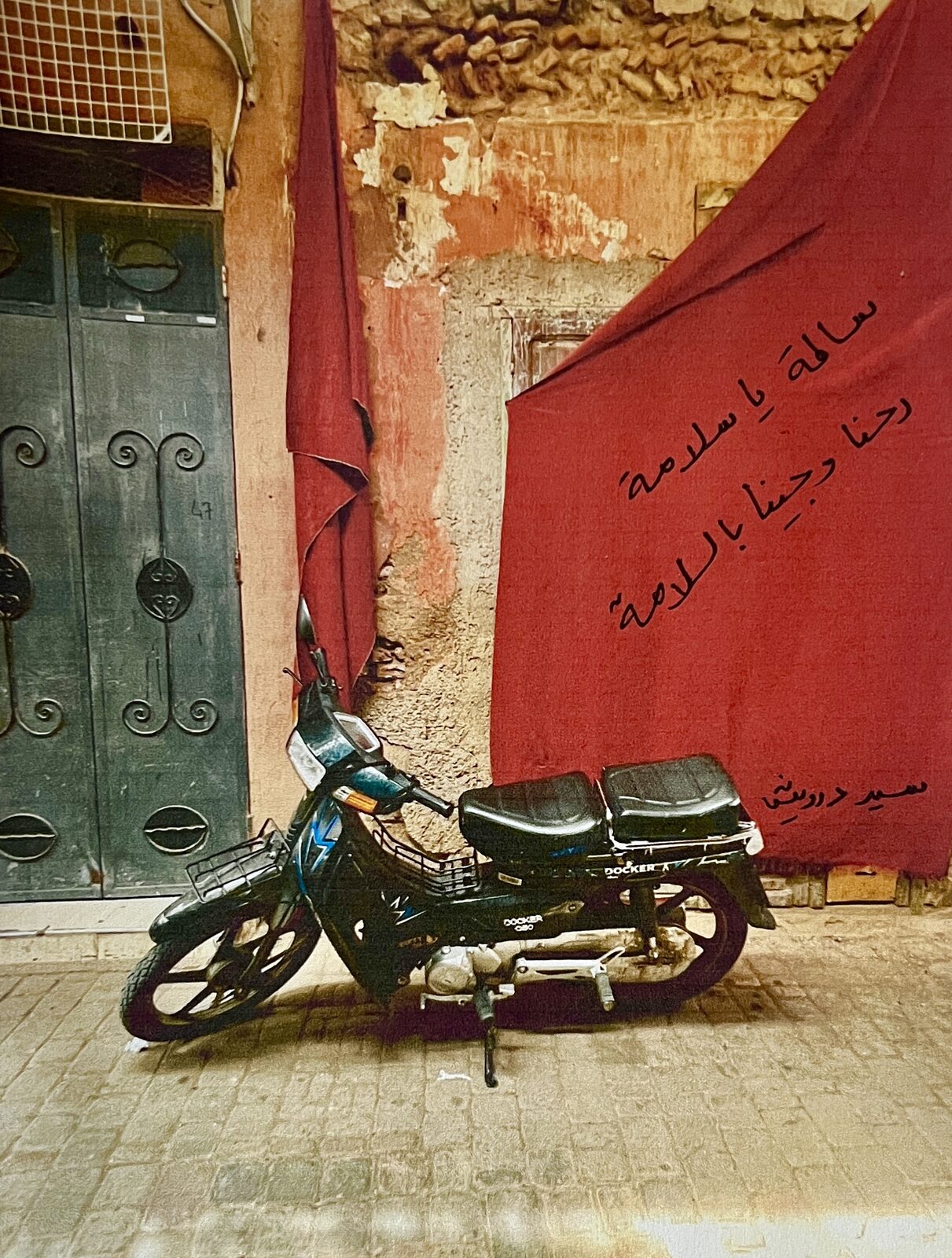Moped before a red cloth with Arabic writing — Shams Al-Fekaiki for ZELZAL