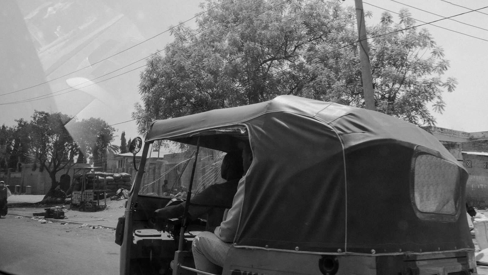 Black-and-white rickshaw on a street under trees — Sumayah Fallatah for ZELZAL