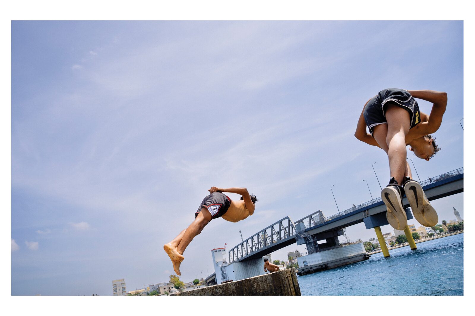 Two boys flipping into the water by a bridge — Zayene Bechir for ZELZAL