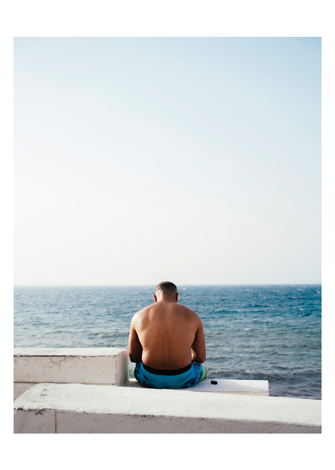 Man sitting on a seawall looking at the sea — Zayene Bechir for ZELZAL