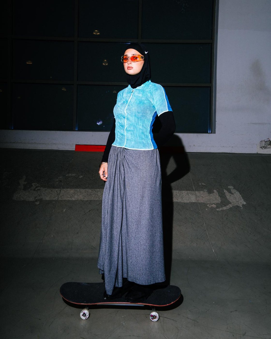 Skater in hijab and orange sunglasses standing on a board at Gooder