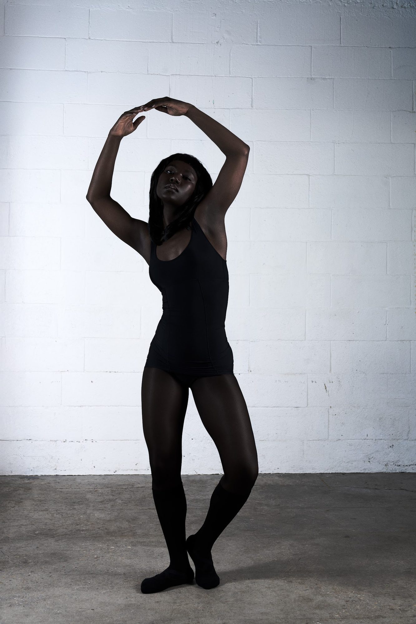 Cover session: dancer in black, arms curved overhead