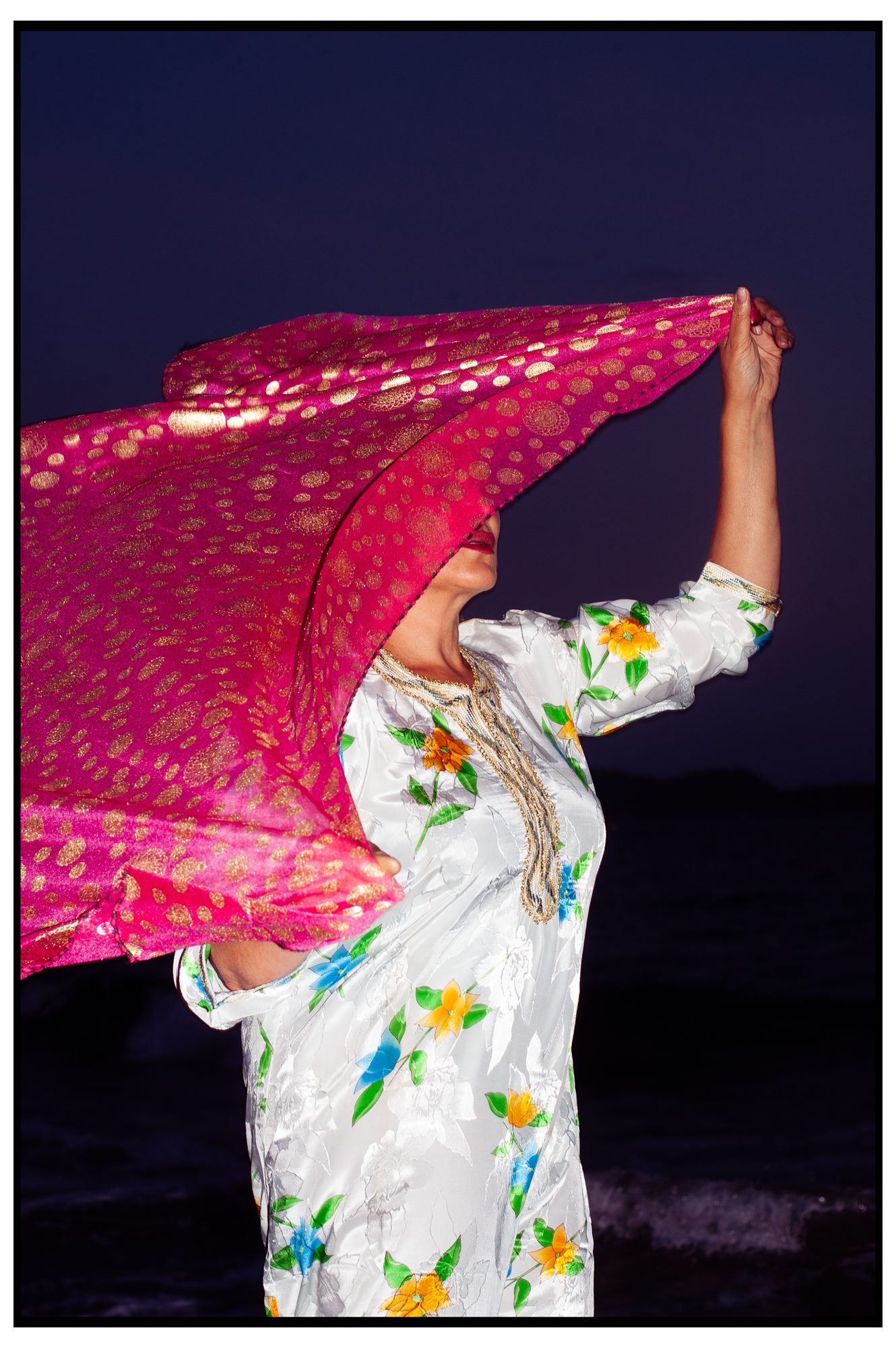 HOME TEAM: woman holding a pink veil overhead at night